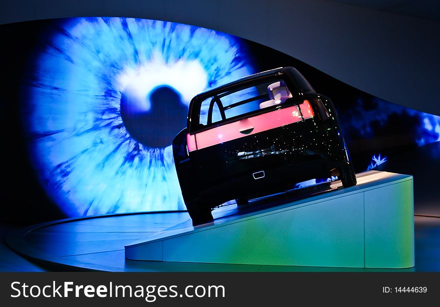 A car displayed in a motor show with eye in the background. A car displayed in a motor show with eye in the background