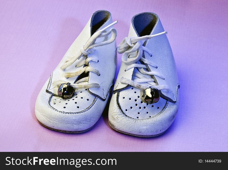 Vintage soft white leather baby shoes on an isolated pink background. Vintage soft white leather baby shoes on an isolated pink background