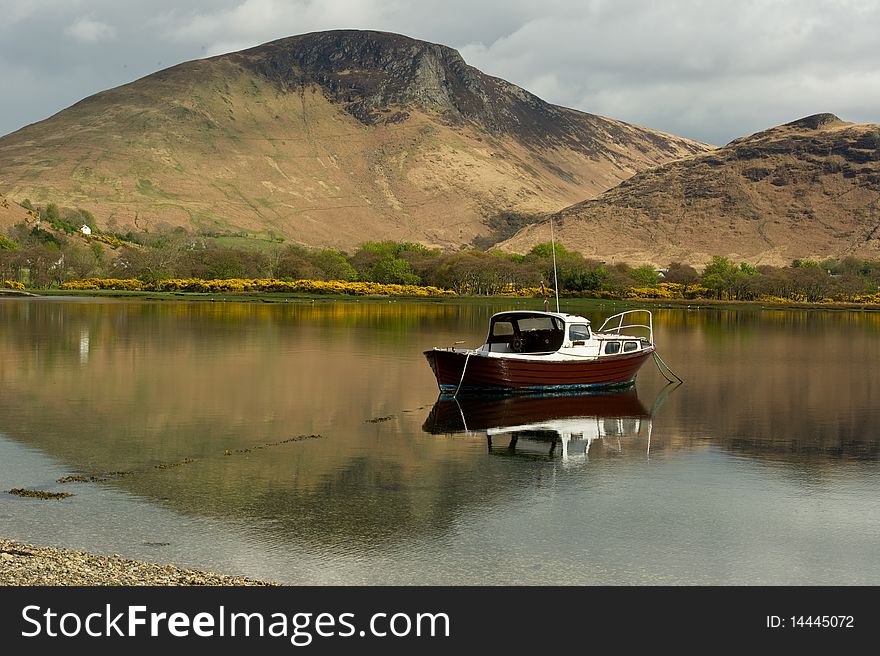 Lochranza loch with mountain reflections and copy  space with boat.