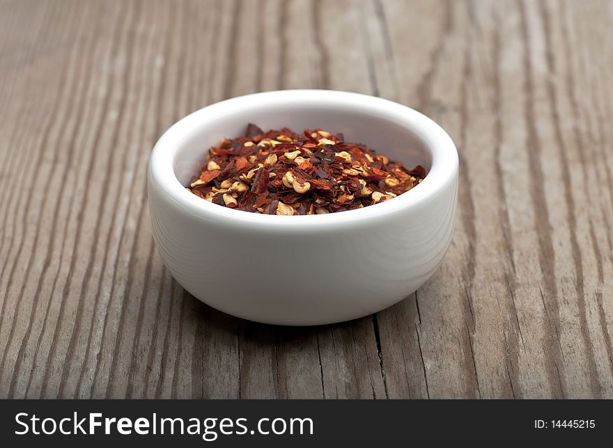 Crushed Chillies In A White Dish, On A Wooden Kitchen Table