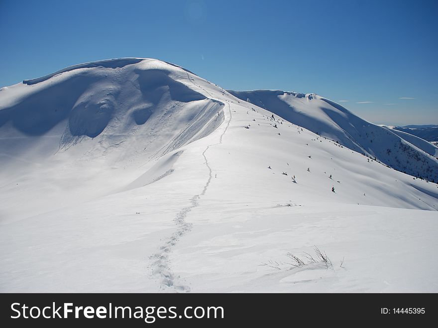 A track in a winter mountain landscape with white tops. A track in a winter mountain landscape with white tops.