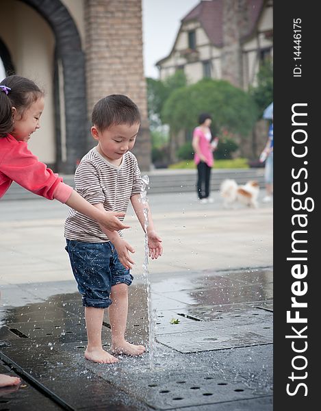 Asian boy and girl play by fountain