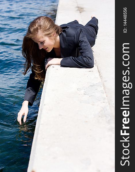 Woman in black suit lying on the border near the water. Woman in black suit lying on the border near the water