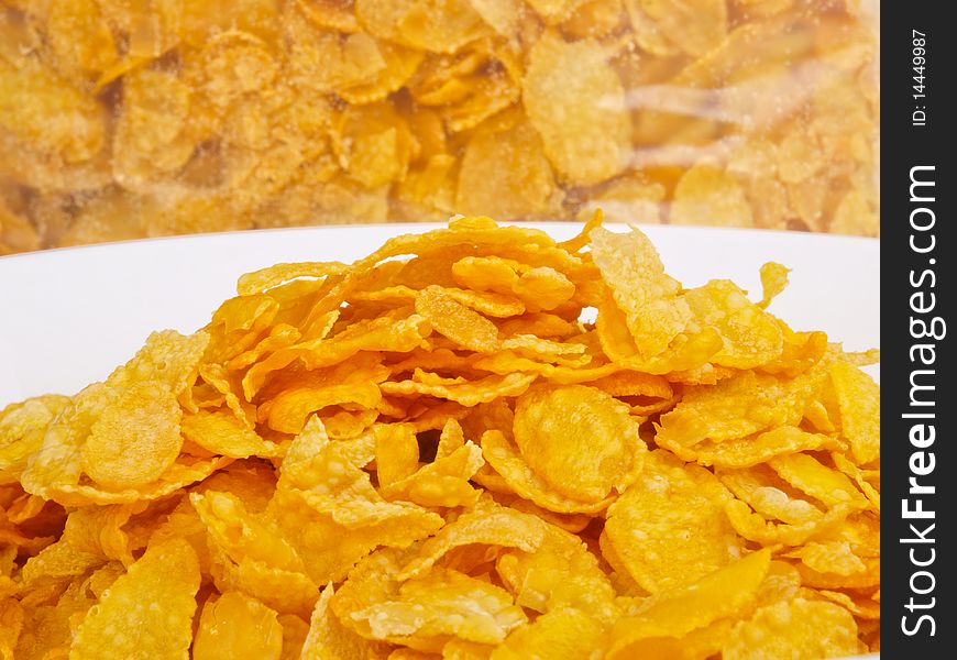 Cornflakes in a bowl. Close up. A back with conrflakes in the background