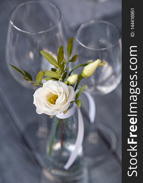 Transparent Modern Setting, Glass Vase With Bouquet Flowers On Table In Restaurant. Wine And Water Glasses Stand On Wooden Table.