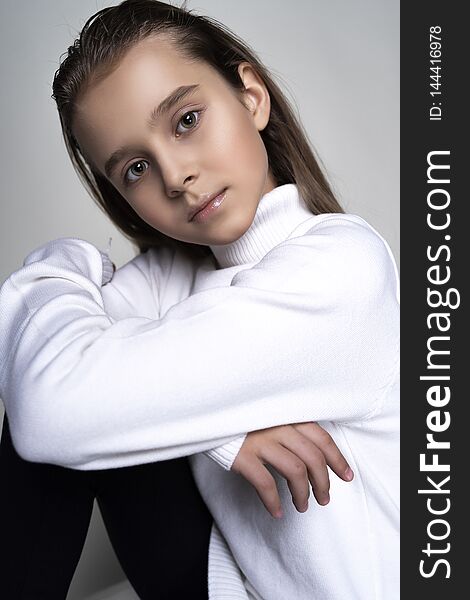 Portrait of a cute teen girl wearing a white turtleneck sweater. Isolated on gray background. Advertising, trendy and commercial design. Copy space. Close-up