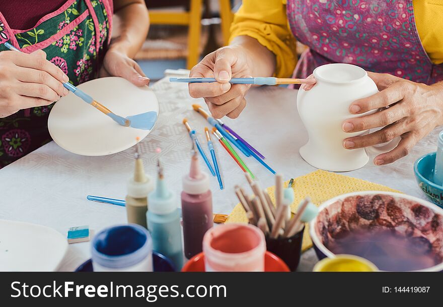 Woman Coloring Handmade Dishes Using Brush And Color