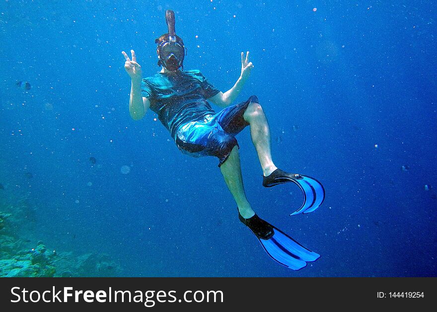 A man with diving goggles and fins snorkeling underwater