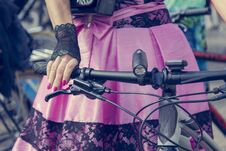 Concept: Women On Bicycles. Hands Holding The Handlebars. Pink Skirt With Black Lace Royalty Free Stock Image