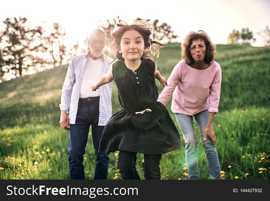 Senior couple with granddaughter outside in spring nature, laughing. Copy space. Senior couple with granddaughter outside in spring nature, laughing. Copy space.