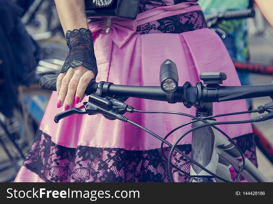 Concept: women on bicycles. Hands holding the handlebars. Pink skirt with black lace
