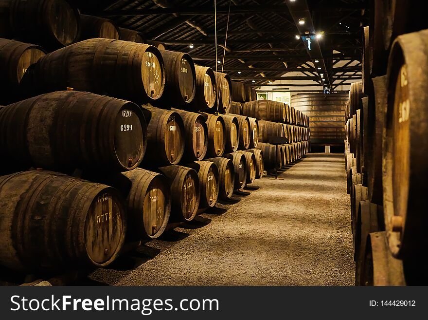 Old aged traditional wooden barrels with wine in a vault lined up in cool and dark cellar in Italy, Porto, Portugal, France