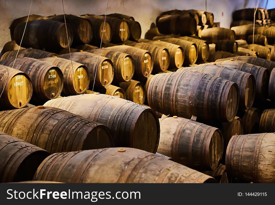 Old aged traditional wooden barrels with wine in a vault lined up in cool and dark cellar in Italy , Porto, Portugal, France