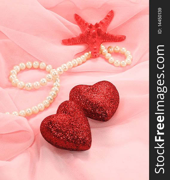 Two sparkling heart, starfish and pearls are on a pink silk. Two sparkling heart, starfish and pearls are on a pink silk