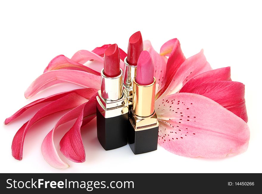 Lipstick and petals of lilies on a white background