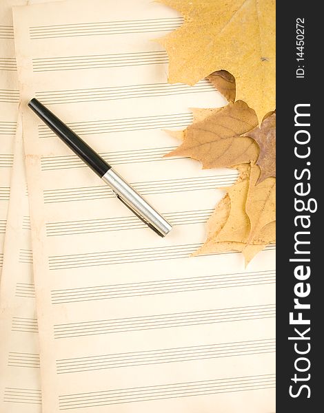 Old sheet music sheet of paper which has a handle and the autumn leaves of maple. Old sheet music sheet of paper which has a handle and the autumn leaves of maple