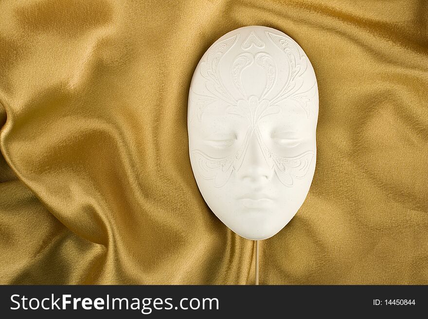 Carnival mask lies on the golden tissue
