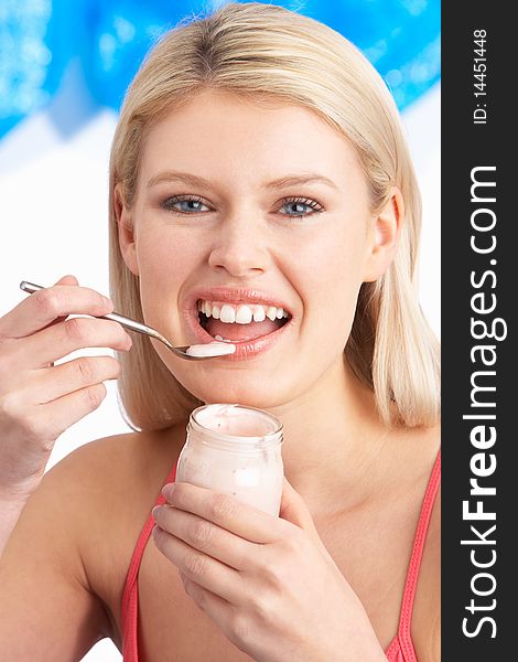 Young Woman Eating Yoghurt In Studio smiling at camera