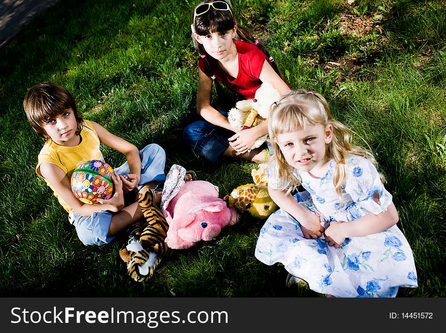 Three children with toys on grass