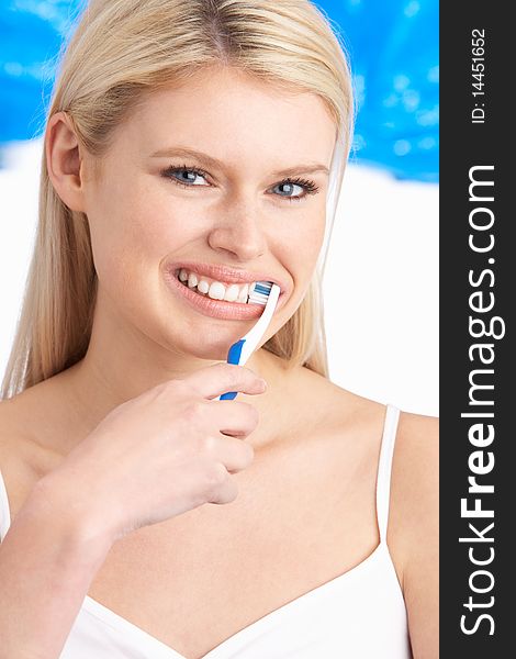 Young Woman Brushing Teeth In Studio At Camera