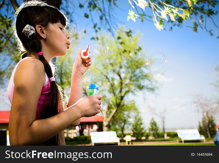 Girl with soap bubbles in park