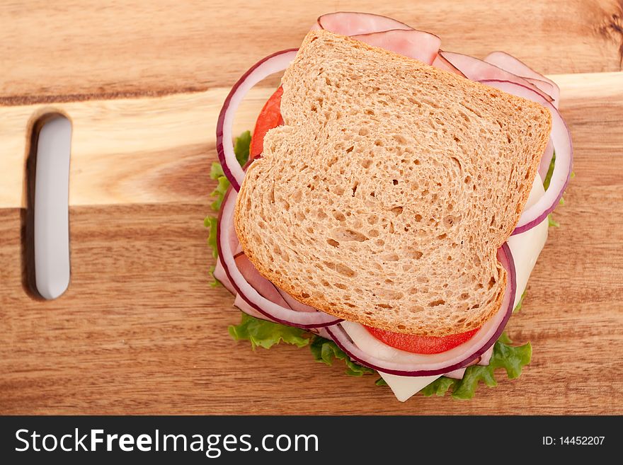 Delicious ham sandwich with whole wheat bread on cutting board. Delicious ham sandwich with whole wheat bread on cutting board