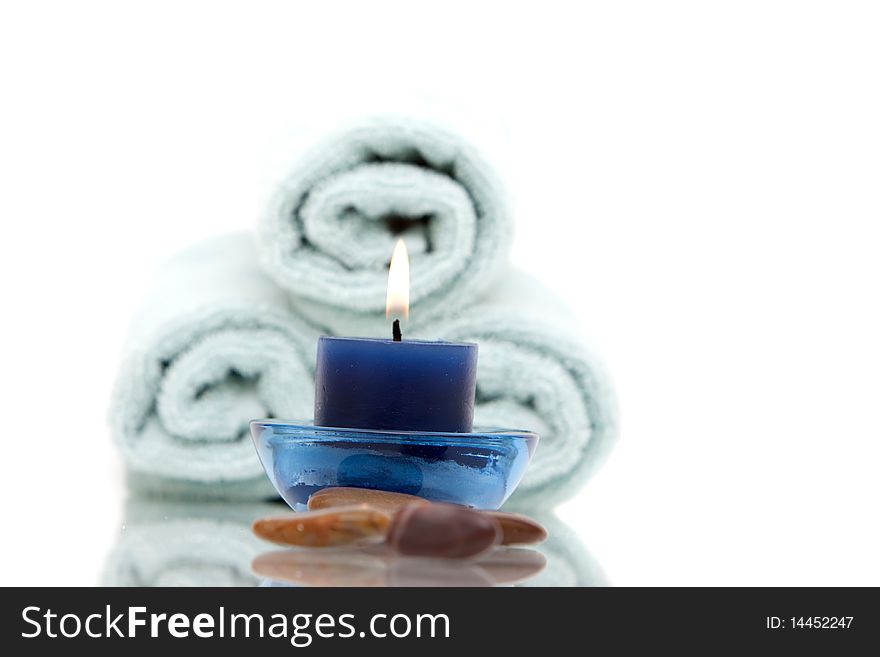 Lit candle in front of stack of towels