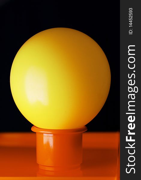 Yellow ball on the orange plastic container over black background