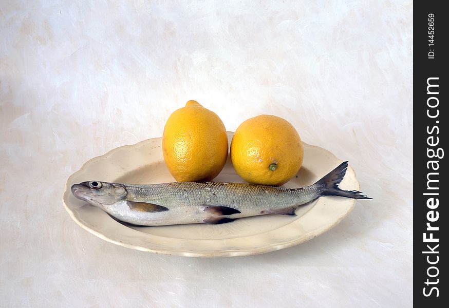 Fish with lemon on plate isolated on painted background