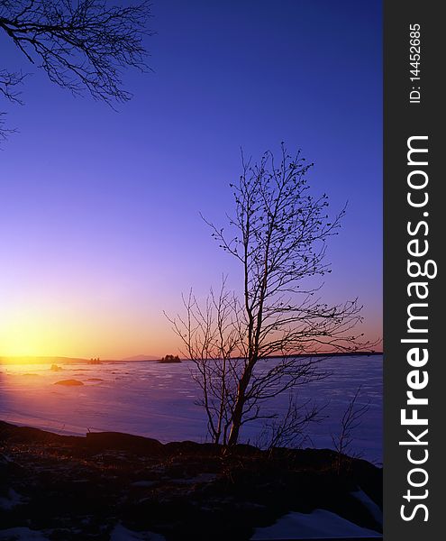 Beautiful winter landscape of snowy lake at sunset