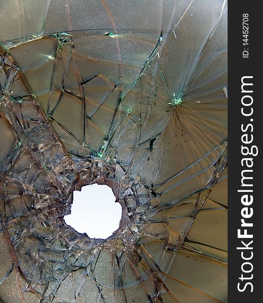 Hole of a crack and splinters in the broken painted glass. Hole of a crack and splinters in the broken painted glass