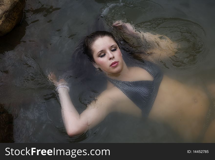 A woman laying on her back in the water with eyes closed and relaxed. A woman laying on her back in the water with eyes closed and relaxed.