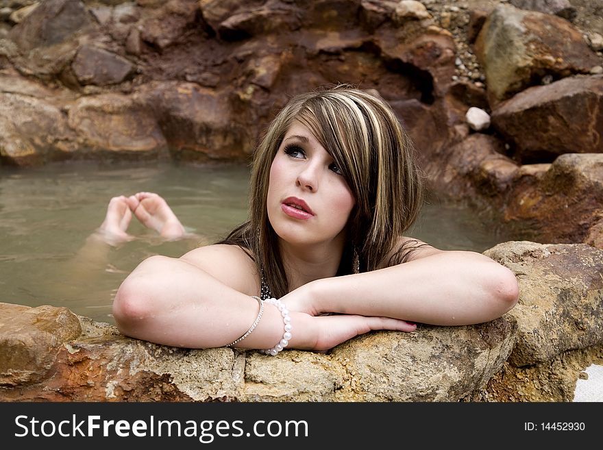 A woman is leaning on her arms in the pool and day dreaming. A woman is leaning on her arms in the pool and day dreaming.