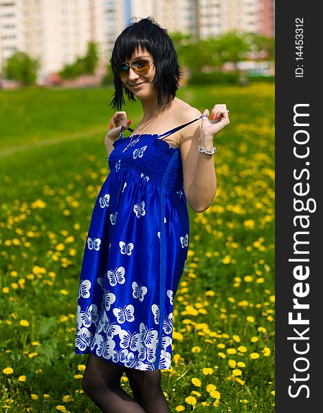 Summer girl in a blue dress against a background of green grass. Summer girl in a blue dress against a background of green grass