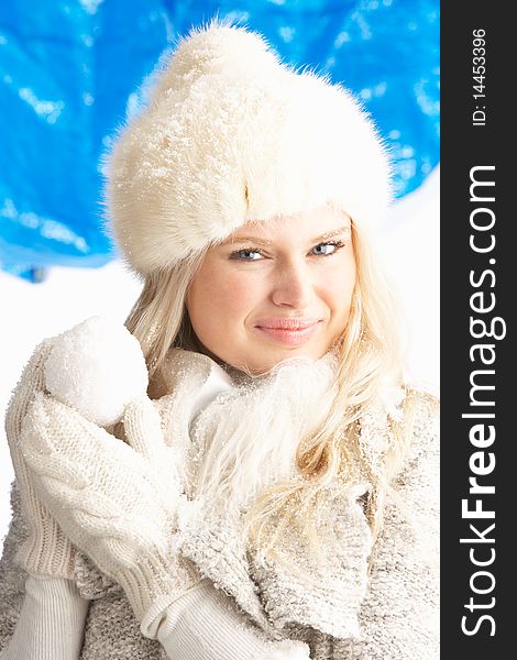 Young Woman Wearing Warm Winter Clothes And Fur Hat Holding Snowball In Studio. Young Woman Wearing Warm Winter Clothes And Fur Hat Holding Snowball In Studio