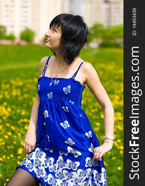 Summer girl in a blue dress against a background of green grass. Summer girl in a blue dress against a background of green grass