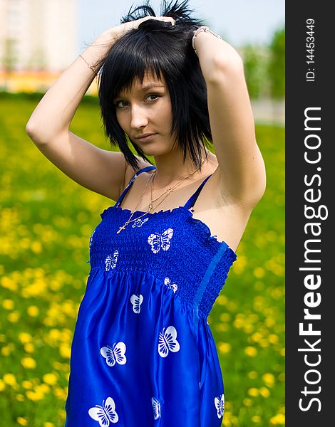 Summer girl in a blue dress against a background of green grass. Summer girl in a blue dress against a background of green grass