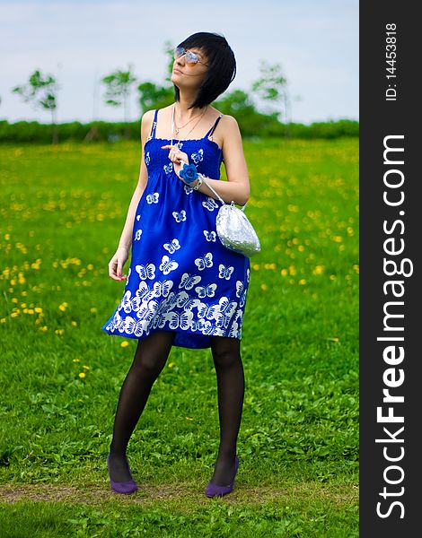 Summer girl in a blue dress against a background of green grass. Summer girl in a blue dress against a background of green grass