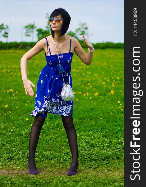 Summer girl in a blue dress against a background of green grass. Summer girl in a blue dress against a background of green grass