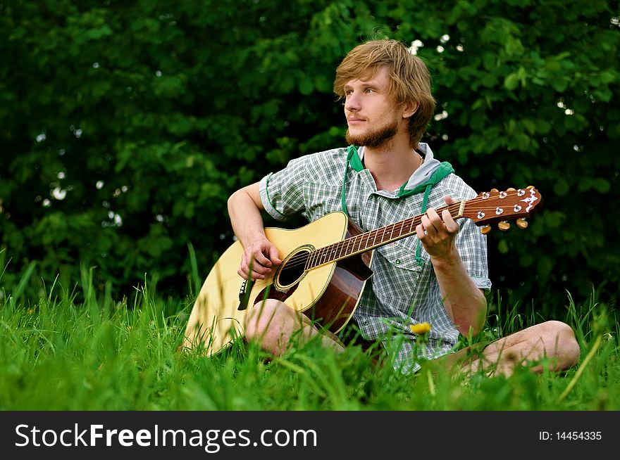 Young man with guitar beside trees. Young man with guitar beside trees