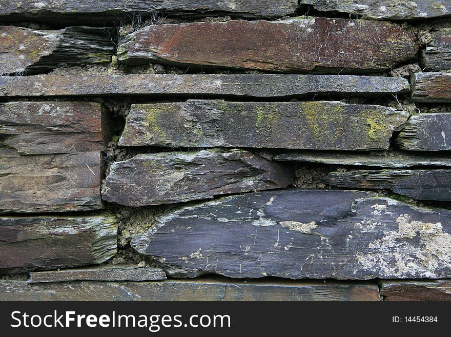 This is a picture of an old stone wall, made up of many different colored stone.