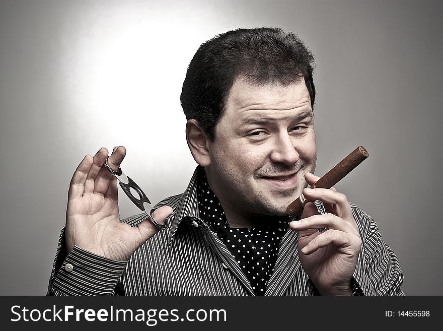 Handsome man holding a cigar and a cigar clipper smiling to the viewer. Handsome man holding a cigar and a cigar clipper smiling to the viewer.