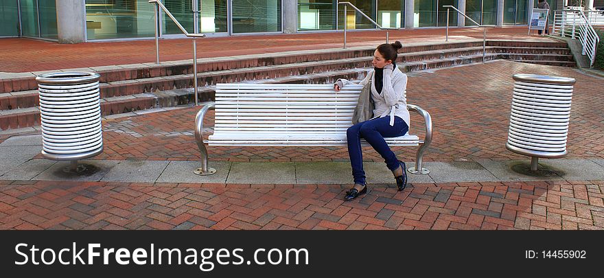 Young beautiful woman sitting on a bench in one of the UK parks . Young beautiful woman sitting on a bench in one of the UK parks .