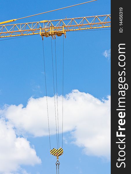 Crane hook over blue sky with clouds