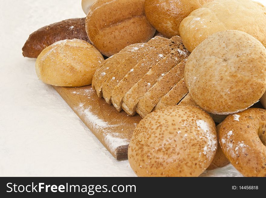 Different types of bread on a wooden board sprinkled with flour