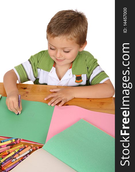 Young blond boy writing with crayons on colored paper. Young blond boy writing with crayons on colored paper