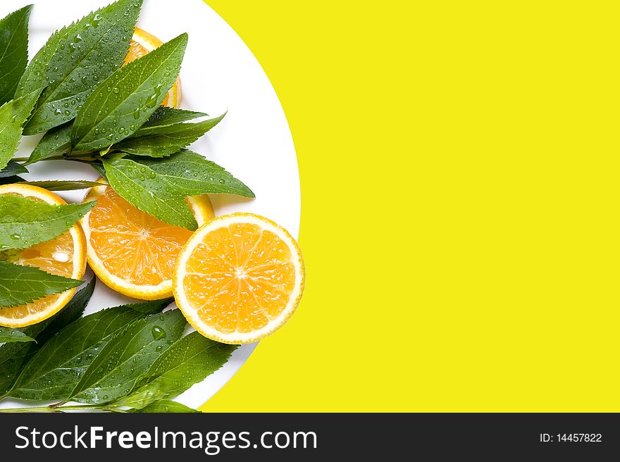 Orange with leaves on the yellow background. Orange with leaves on the yellow background