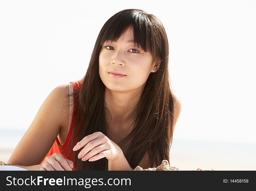 Young Woman Relaxing On Beach At Camera