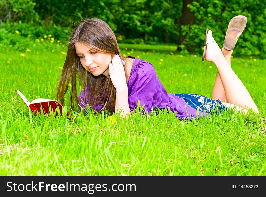 Young smiling woman reading on the grass. Young smiling woman reading on the grass