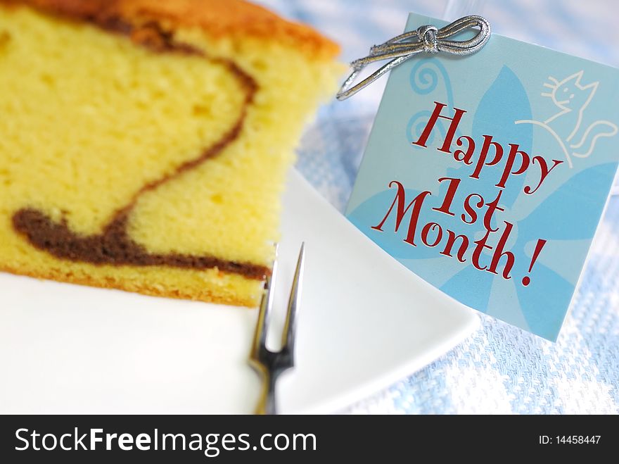 A slice of mouth watering butter cake with card beside for a baby's first month anniversary. Suitable for celebrations, festivals, and food and beverage concepts. A slice of mouth watering butter cake with card beside for a baby's first month anniversary. Suitable for celebrations, festivals, and food and beverage concepts.